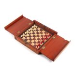 A travelling chess set in a folding mahogany case (lacks one pawn), 20cms wide.