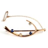 A yellow metal wishbone brooch set with two diamonds and two pale sapphires, 5cms wide, 6.6g.