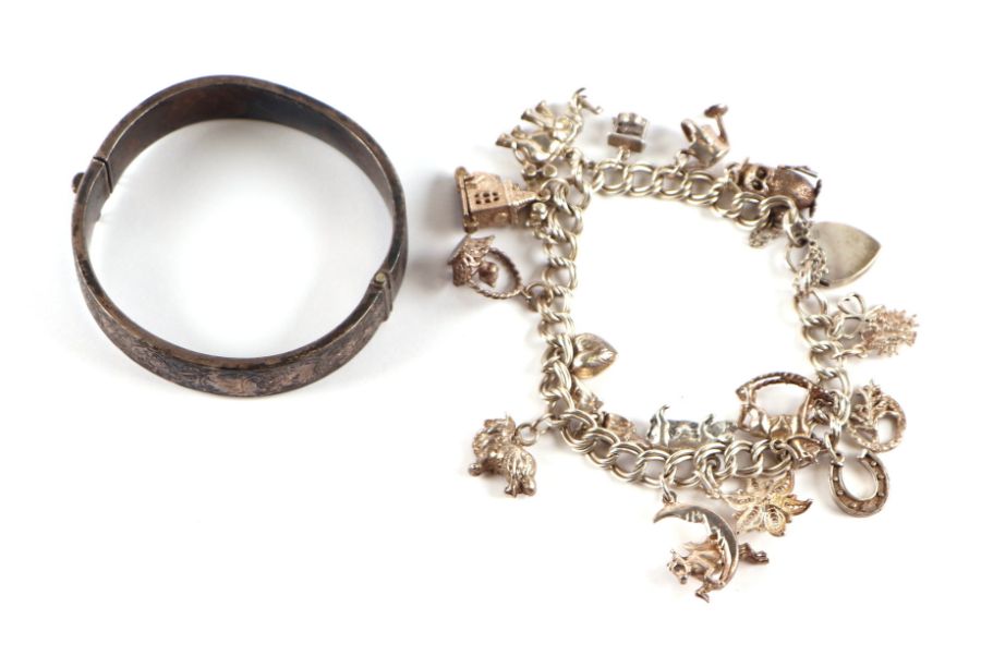A silver charm bracelet; together with a hinged silver bangle, 71g (2).