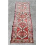 A Persian Azari runner with multiple hexagonal medallions on a beige ground, 350 by 90cms (374).