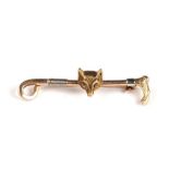 A 15ct gold bar brooch in the form of a riding crop and a fox mask, 6.4g.
