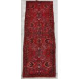 A Persian runner with repeated floral design with floral borders, on a red ground, 390 by 110cms (