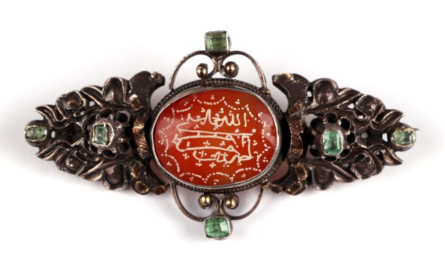 An Austro-Hungarian white metal brooch set with a central oval hardstone cabochon and six pale green