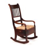 A George III elm rocking chair with slat back, upholstered seat and box base with single drawer.