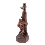 A Black Forest / Anri figural table lamp depicting a musician leaning against a tree, 32cms high.