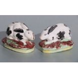 A pair of 19th century Staffordshire figures in the form of recumbent black & white rabbits, each