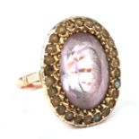A late 19th century 9ct gold ring set with a large oval pale amethyst within a seed pearl border,