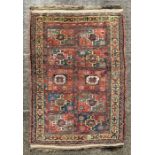 A Northeast Persian Quchan Kurdish rug with central repeating medallions on a red ground within a