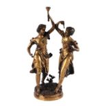 After Moreau - a cast bronze figural group in the form of two hand maidens, one holding a torch