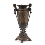 A classical cast bronze urn with mask handles, grotesque supports and quatrefoil circular base,