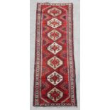 A Persian hand knotted runner with stylised geometric design, on a beige ground, 290 by 90cms (