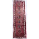 A Persian hand knotted runner with repeating central guls within a multi floral border, 315 by 90cms