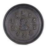 An ebonised pottery roundel depicting Charles Dickens and book characters, 37cms diameter.
