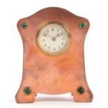 An Arts & Crafts copper mantle alarm clock with inset green glass cabochons, 10cms high.
