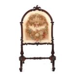 A 19th century carved mahogany firescreen with embroidered panel depicting flowers, on vase shaped