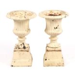 A pair of painted cast iron Campana urns on stands, 51cms high (2).