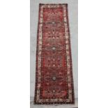 A Persian runner with stylised flower design, on a red ground, 420 by 105cms ((73/19).