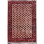 A Persian hand knotted woollen runner with repeated design within a geometric border, on a beige