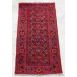 A Persian Turkoman hand knotted runner with repeat geometric design, on a red ground, 230 by
