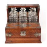 A late 19th century oak three bottle Tantalus, the front section opening to reveal compartments