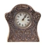 An Edwardian silver fronted Art Nouveau design table clock, the white dial with Roman numerals,