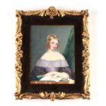 A portrait miniature on ivory depicting a young girl wearing a lavender dress reading a book, framed