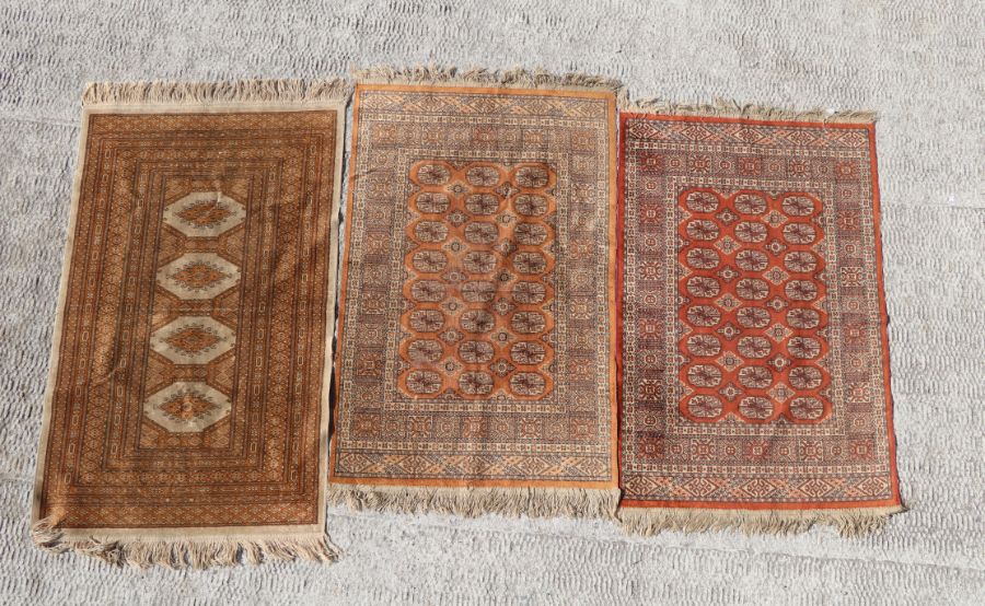 Three small machine made Persian Bokhara rugs, each approx 65 by 100cms (3).