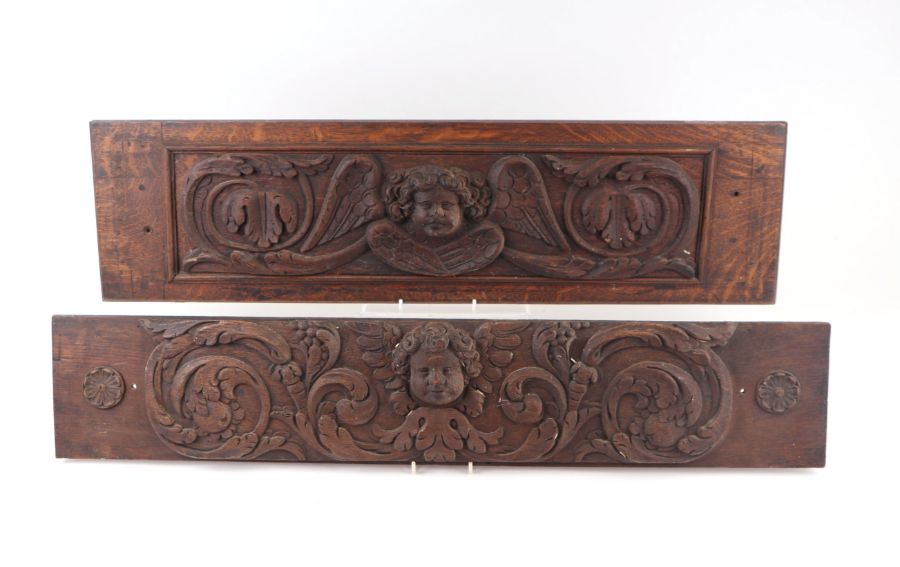 A 17th century style carved oak panel depicting a cherub within oak leaf scrolls, 80cms wide;