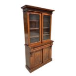 A Victorian mahogany bookcase on cupboard, the pair of glazed doors enclosing a shelved interior,