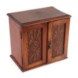 An early 20th century oak smoker's cabinet with lift-up top and two panelled doors enclosing a