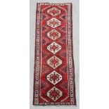 A Persian hand knotted runner with stylised geometric design, on a beige ground, 290 by 90cms (