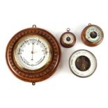 A wall aneroid barometer in a carved oak case, 30cm diameter; and three similar barometers (4).