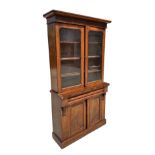 A Victorian mahogany bookcase on cupboard, the pair of glazed doors enclosing a shelved interior,