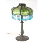 A table lamp, the metal base with moulded flutes and a mottled green glass shade with suspended