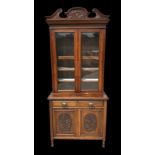 An Edwardian walnut bookcase on cupboard with twin swan necked arched pediment above a pair of