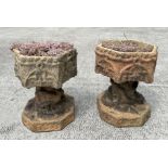 A pair of well weathered terracotta planters on stands of hexagonal form, on intertwined snake