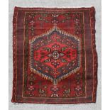 A Persian Hamadan hand knotted woollen rug with stylised design within borders, on a red ground, 140