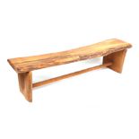 A rustic wooden garden bench on shaped rectangular supports joined by a stretcher, 164cms long.