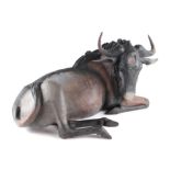 Nichola Theakston MA (modern British) - a ceramic reclining wildebeest sculpture, 75cm wide.