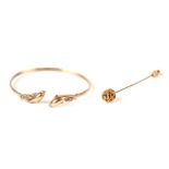 A 9ct gold bangle with dolphin terminals, 8g; together with a costume jewellery stick pin with acorn