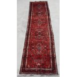 A Persian Tabriz long woollen runner with six central floral medallions, on a red ground, 420 by