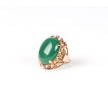 A yellow metal dress ring set with a large green cabochon. Approx UK size I, 10g