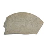 A stone fragment, possibly 17th century of near quarter circle form, carved with scrolling foliage