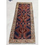 A Persian hand knotted Afshar runner with central stylised design, on a navy ground, 290 by 110cms.