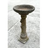 A well weathered reconstitiuted stone bird bath, the column having rose decoration, 28cm diameter.