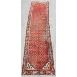 A Persian Saraband runner with all over design within stylised borders, on a red ground, 390 by