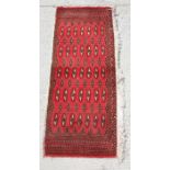 A Persian Turkoman woollen hand-made small rug with geometric designs on a red ground, 124 by