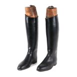 A pair of black riding boots with wooden trees.