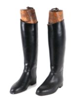 A pair of black riding boots with wooden trees.