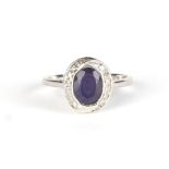 A 9ct white gold dress ring set with a large oval pale blue stone surrounded by diamonds, approx